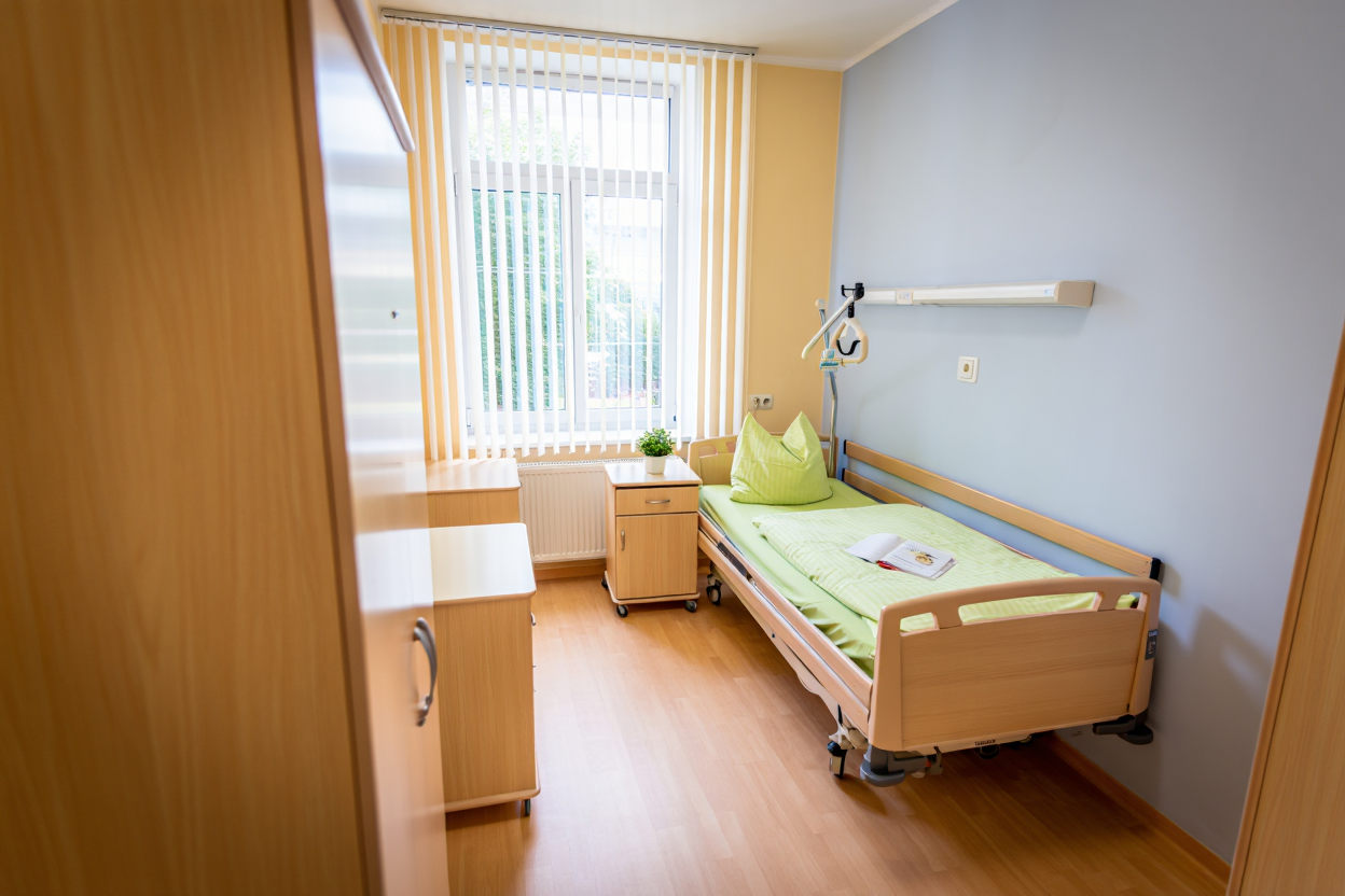 Чистая одноместная палата с медицинской кроватью, тумбочкой и окном с жалюзи — условия пребывания в медицинском вытрезвителе.
